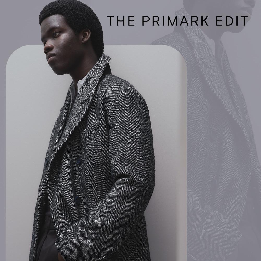 Modello che indossa un cappotto con fantasia a spina di pesce grigio della collezione THE PRIMARK EDIT.