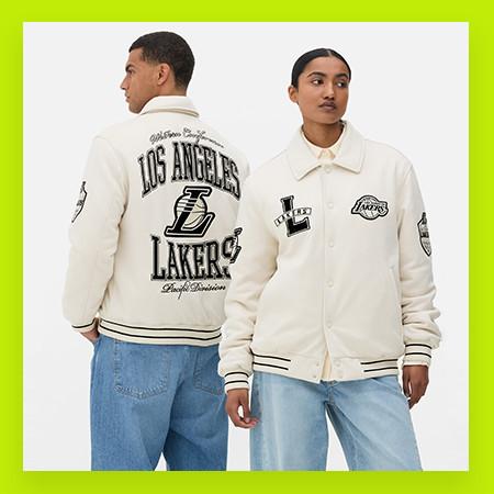 Two people wearing white Los Angeles Lakers varsity jackets with team logos and branding against a bright green border.