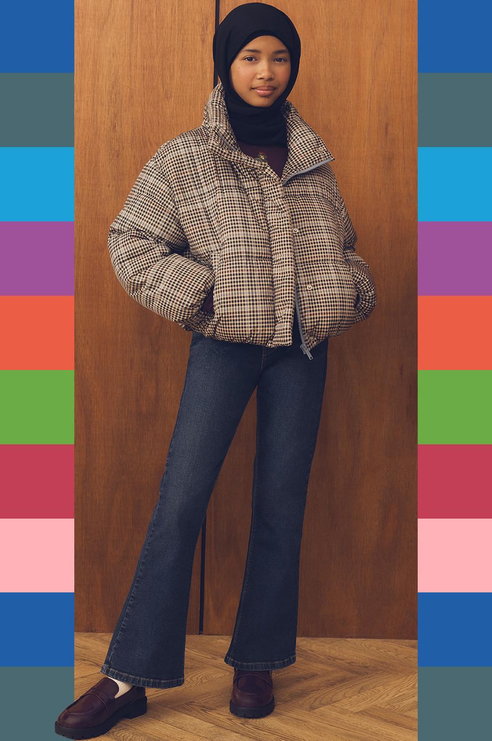 Woman wearing black hijab, brown houndstooth puffer jacket and dark blue flared jeans.