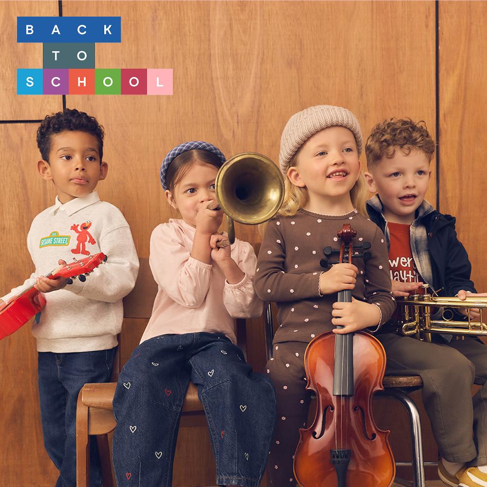 Four children posing with musical instruments including a toy guitar, trombone, cello and trumpet.