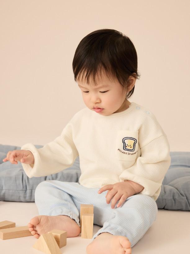 Child wearing grey and blue colour-block hooded jacket with matching dark trousers and blue trainers.