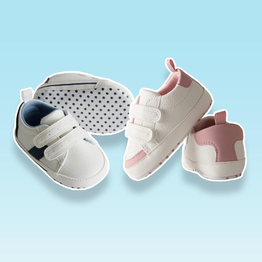 Three white baby sneakers with hook-and-loop straps, featuring navy and pink color accents.