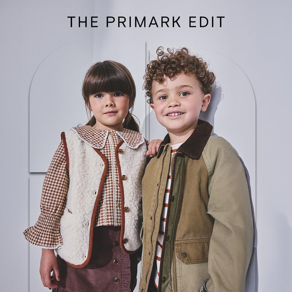 Two children smiling in THE PRIMARK EDIT fall clothing collection with layered jackets and vests.