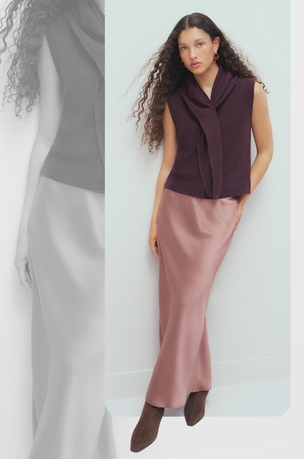 Model wearing burgundy sleeveless cowl neck top with pink satin midi skirt and brown ankle boots.