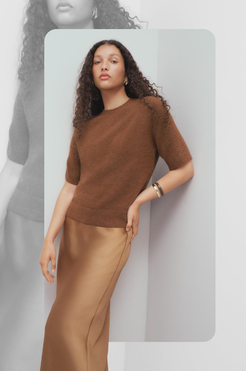 Model wearing brown short-sleeved knit sweater with gold hoop earrings and camel pants.