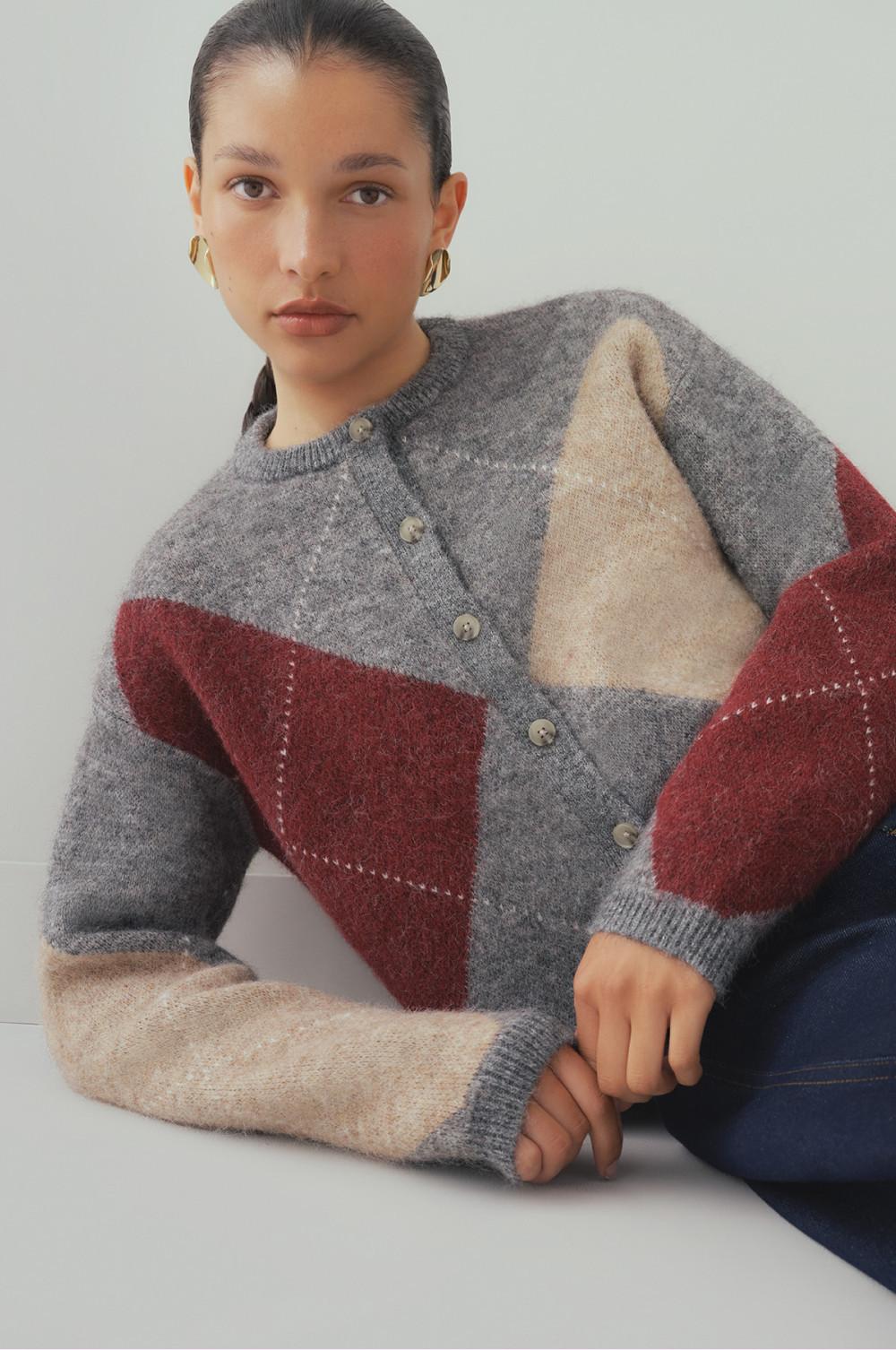 Model wearing gray button-front cardigan with burgundy and beige color-block pattern and gold hoop earrings.