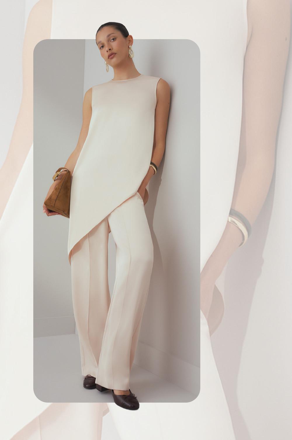Model wearing cream sleeveless tunic and matching wide-leg pants, holding a tan leather bag.