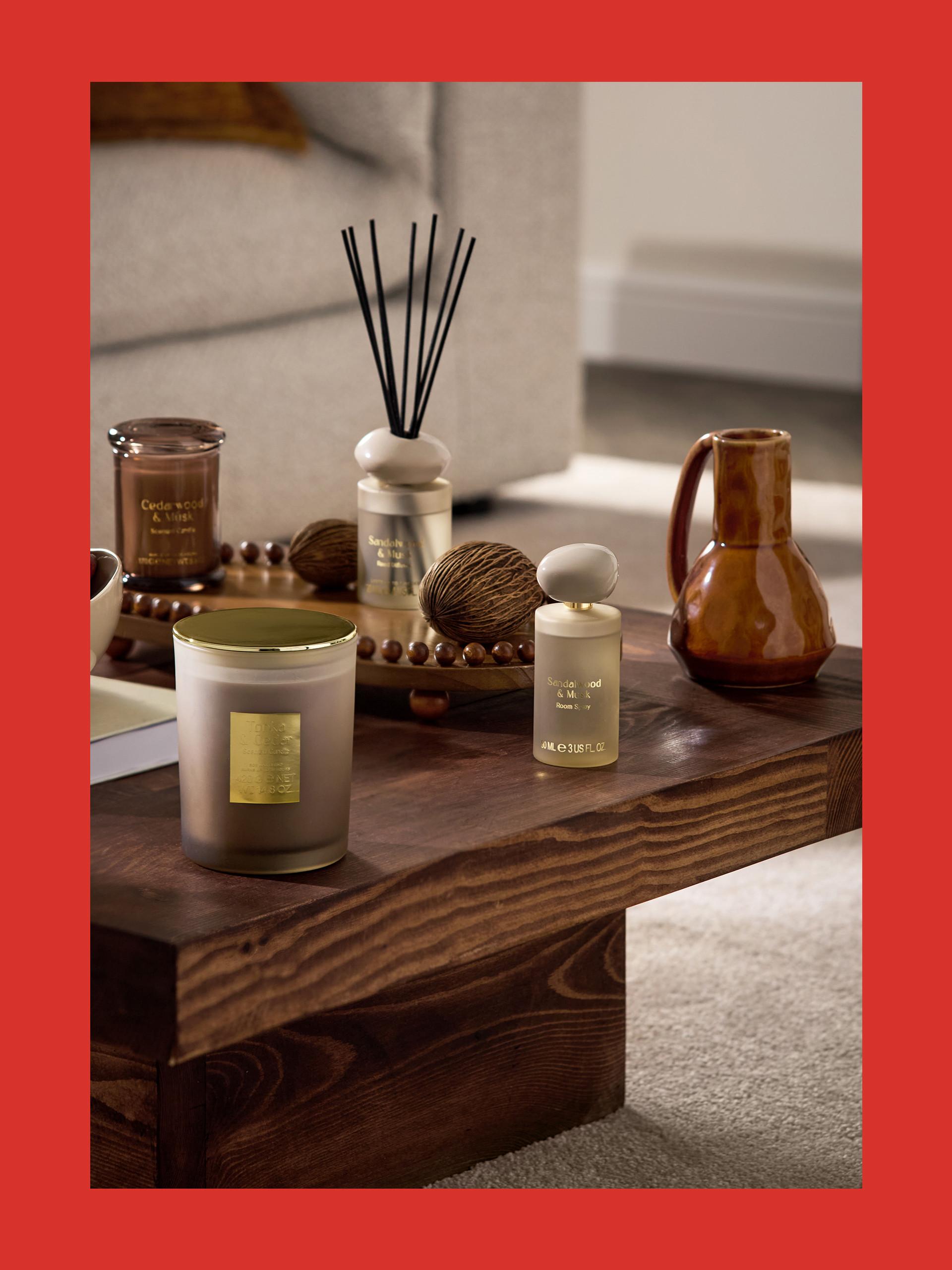 Collection of Sandalwood & Musk home fragrance products including candle, diffuser and room spray on wooden table.