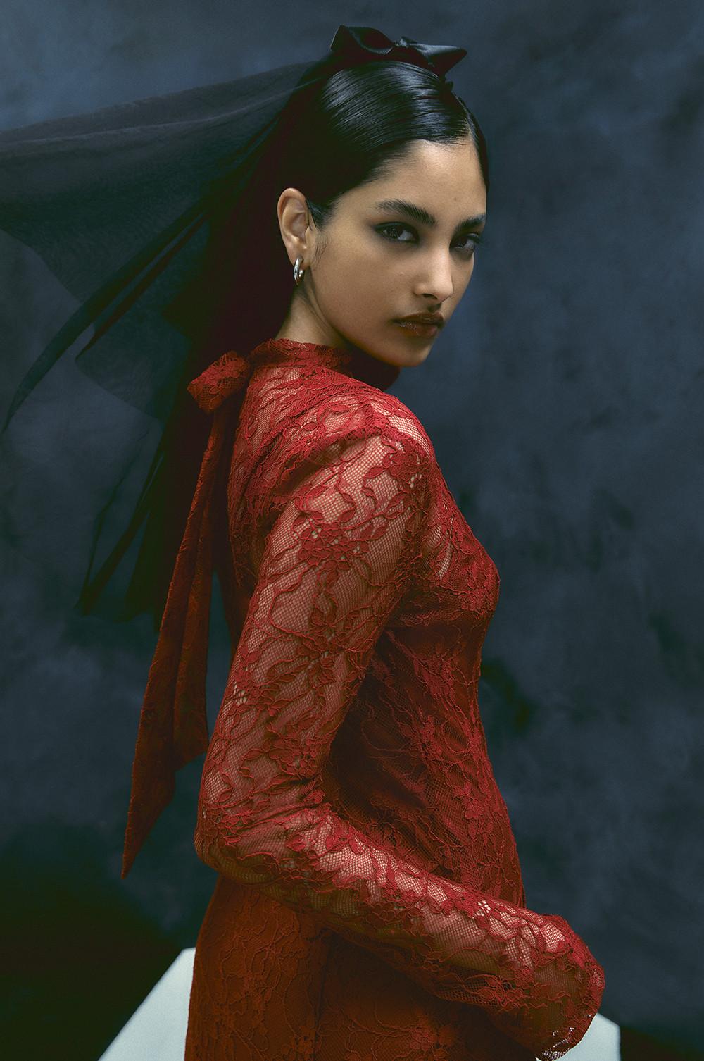 Le mannequin porte une robe en dentelle rouge et un nœud noir dans les cheveux