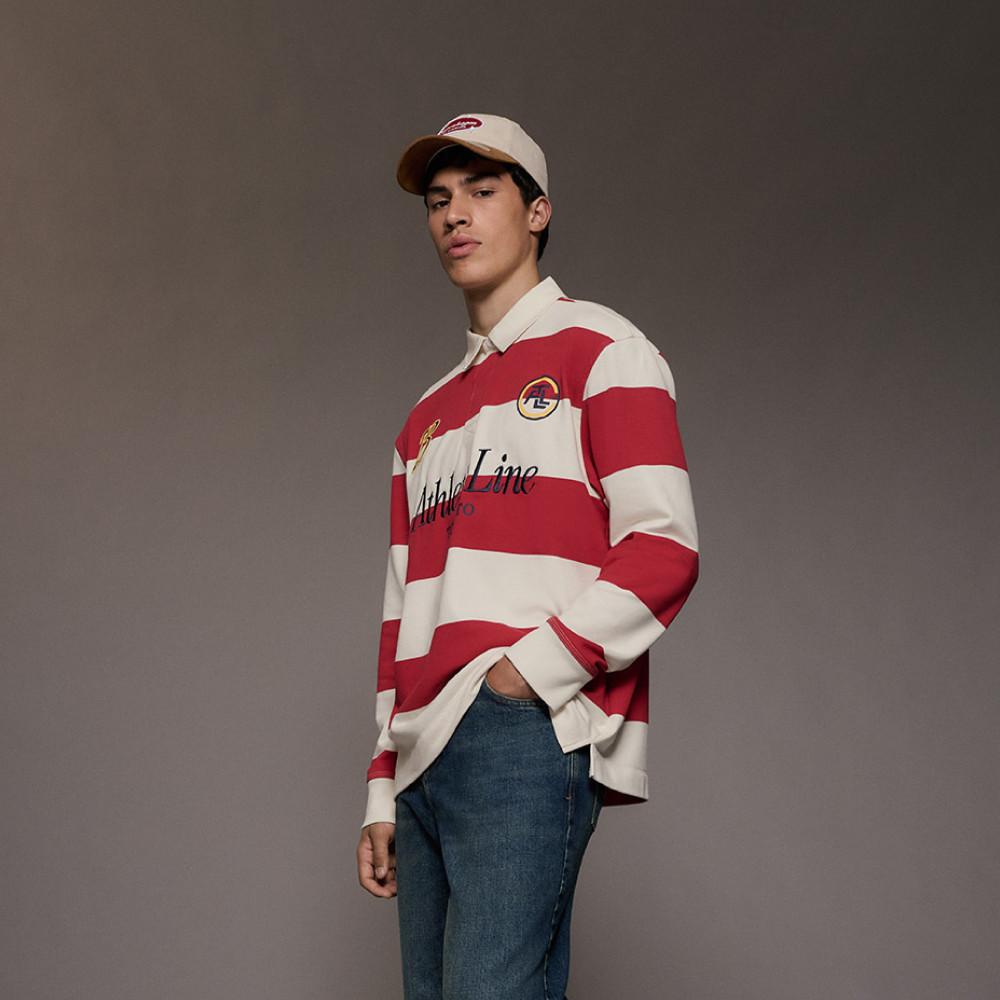 Model wearing red and cream striped rugby shirt with Athlo Line text and matching baseball cap with jeans.