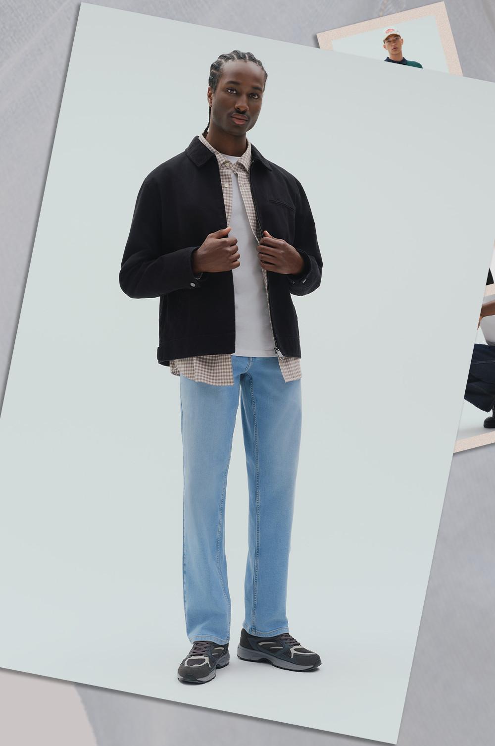 Model wearing black jacket over checked shirt and white tee, styled with light blue jeans and sneakers.