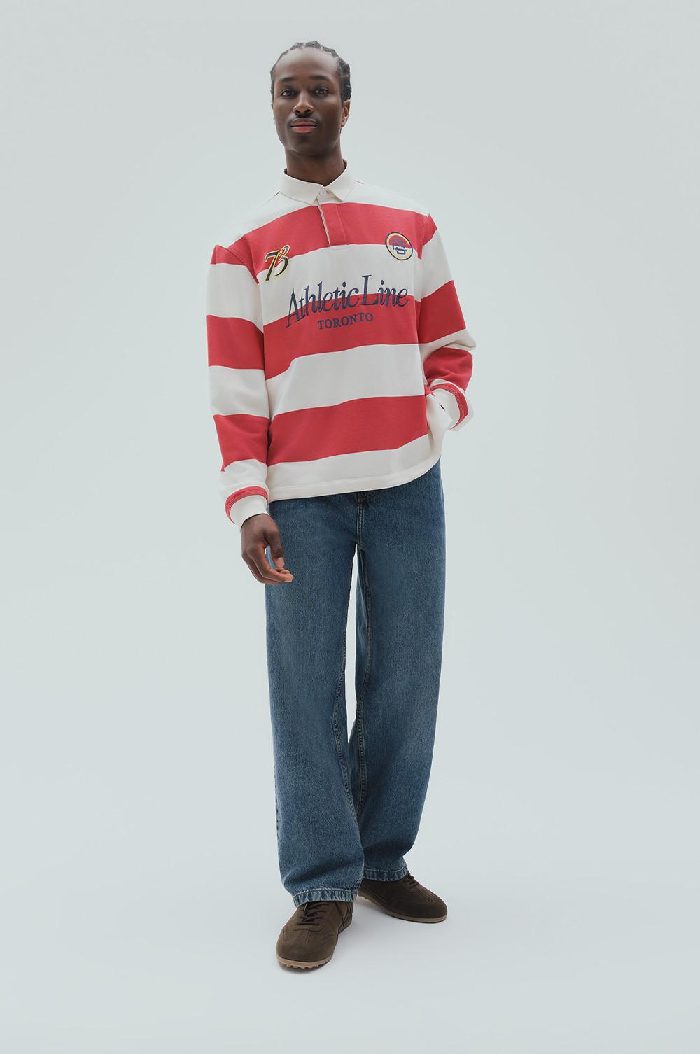 Model wearing red and white striped rugby shirt with Athletic Line Toronto text and blue jeans.