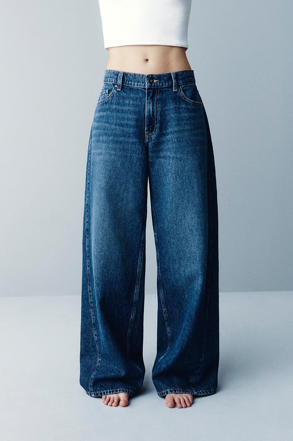 Wide-leg blue denim jeans with high waist and relaxed fit, worn with white top.