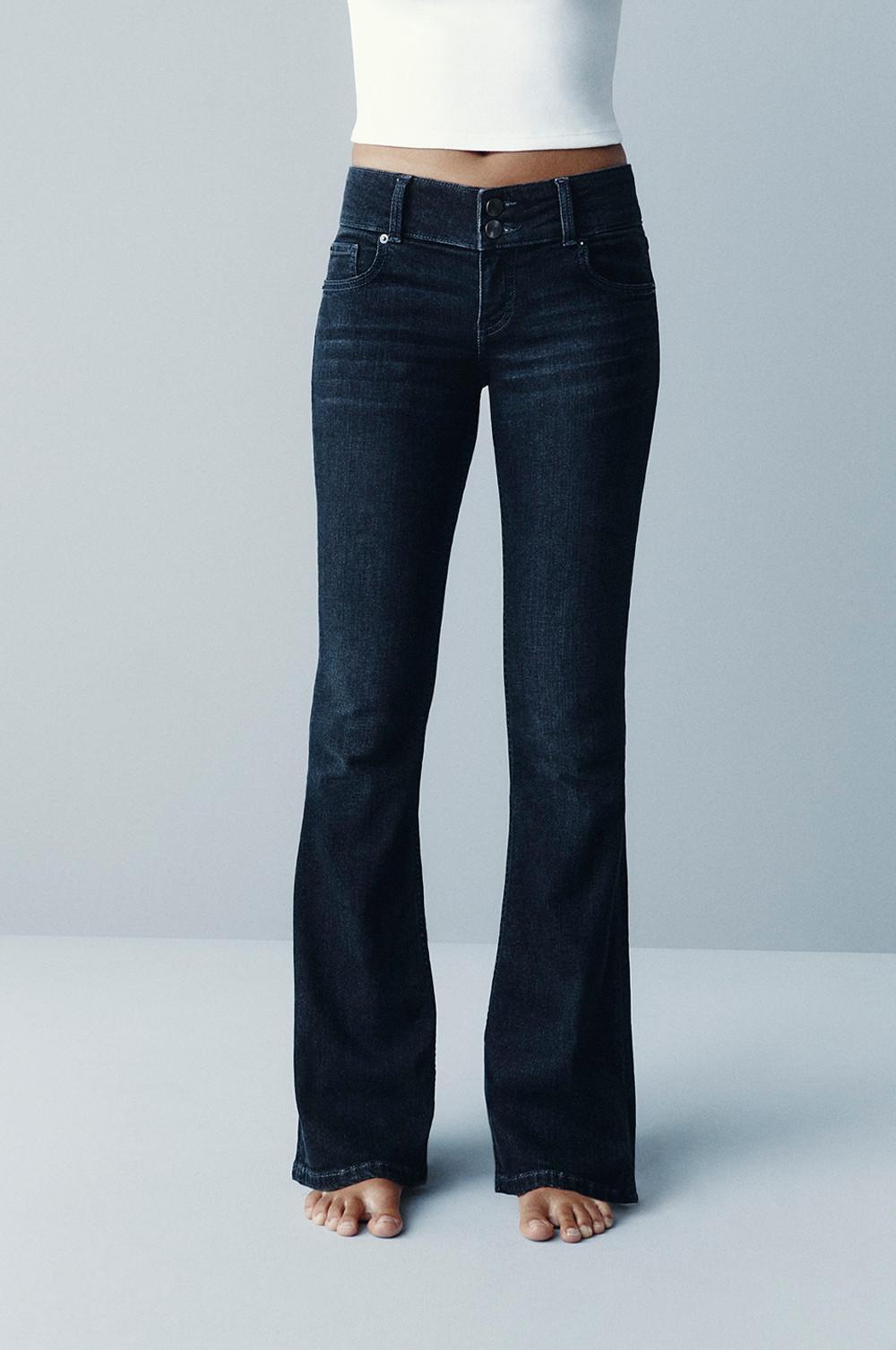 Dark blue flared jeans with high-waisted double button fastening worn with white crop top.
