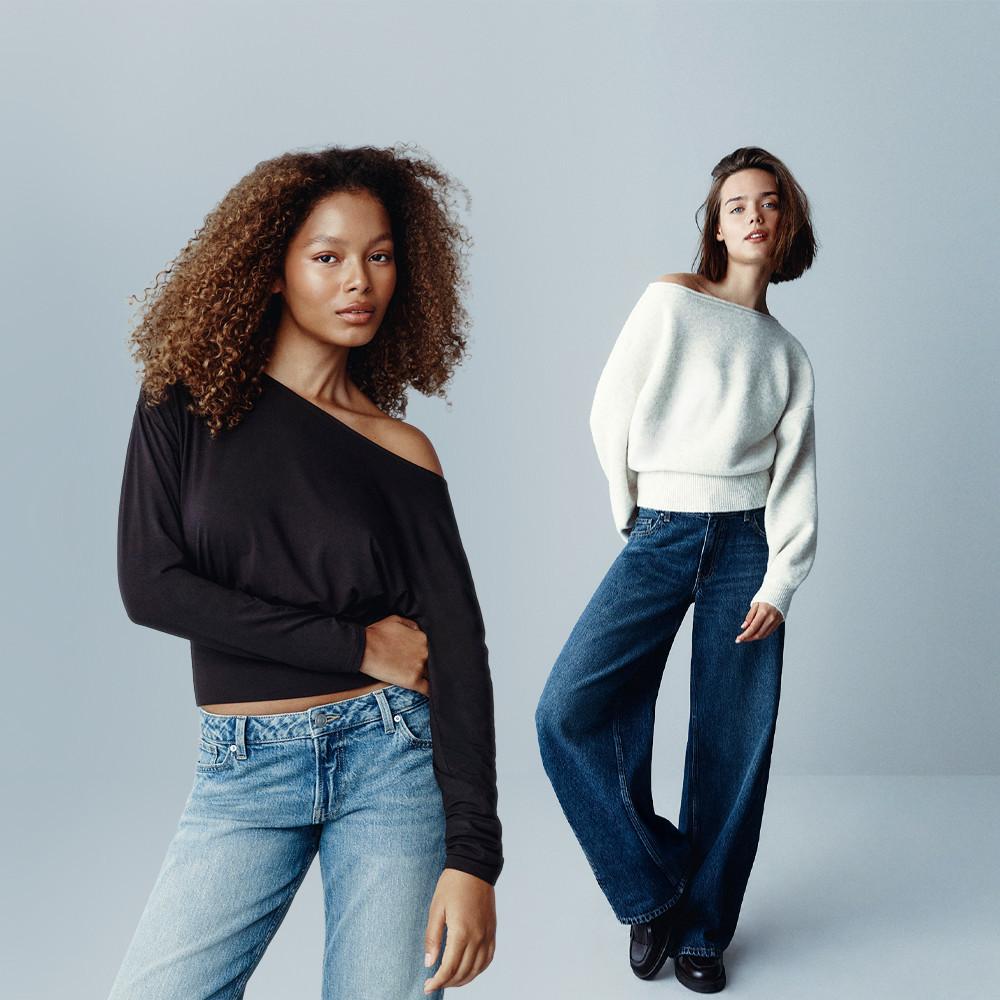 Two models wearing casual wear: one in a black off-shoulder top with light jeans, the other in a cream sweater with wide-leg dark jeans.