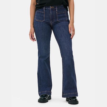 Dark blue flared jeans with front pockets shown on person wearing black top and shoes