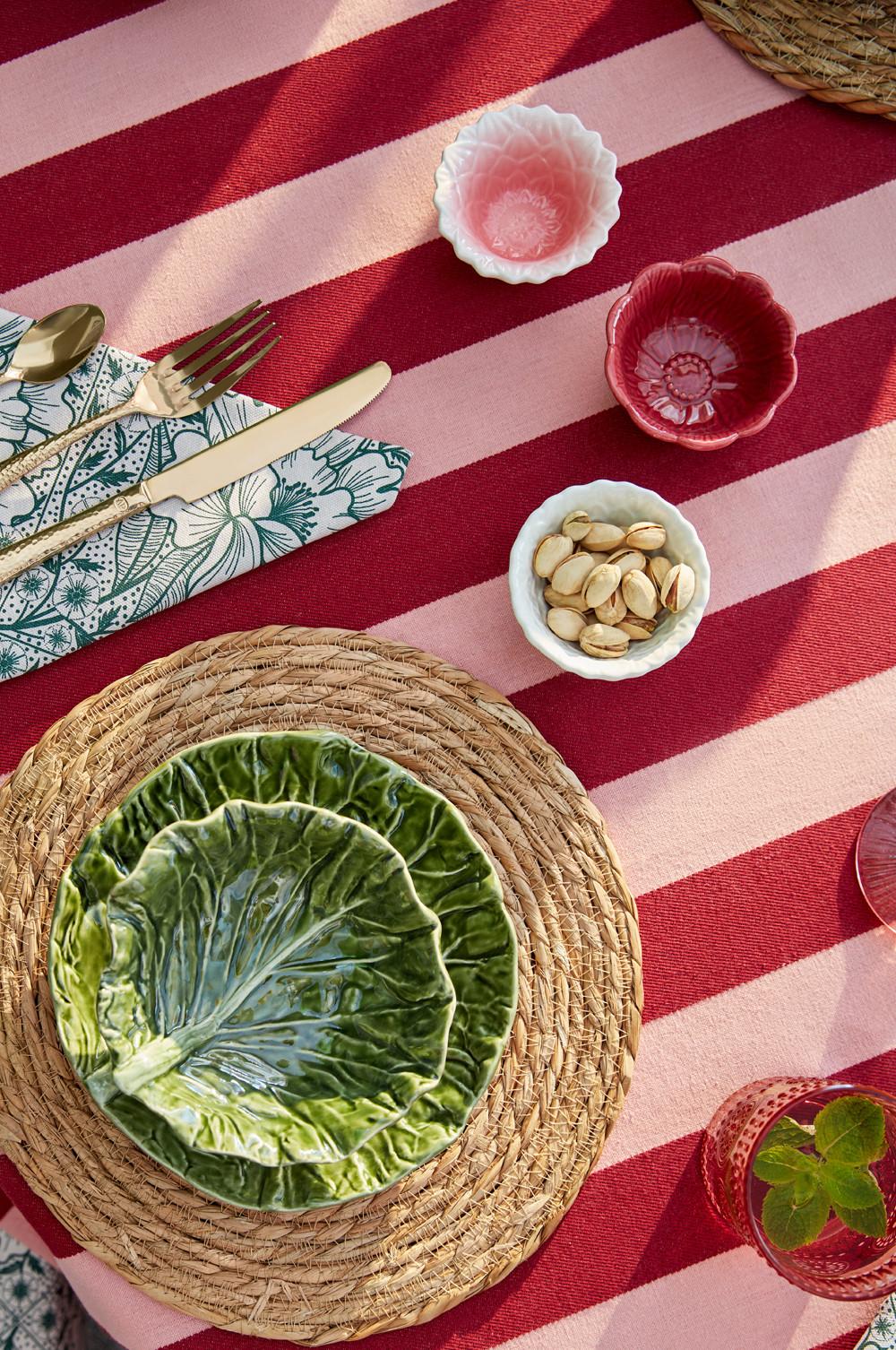 Table set up of leaf bowl, rattan placemat with a pink and red striped tablecloth