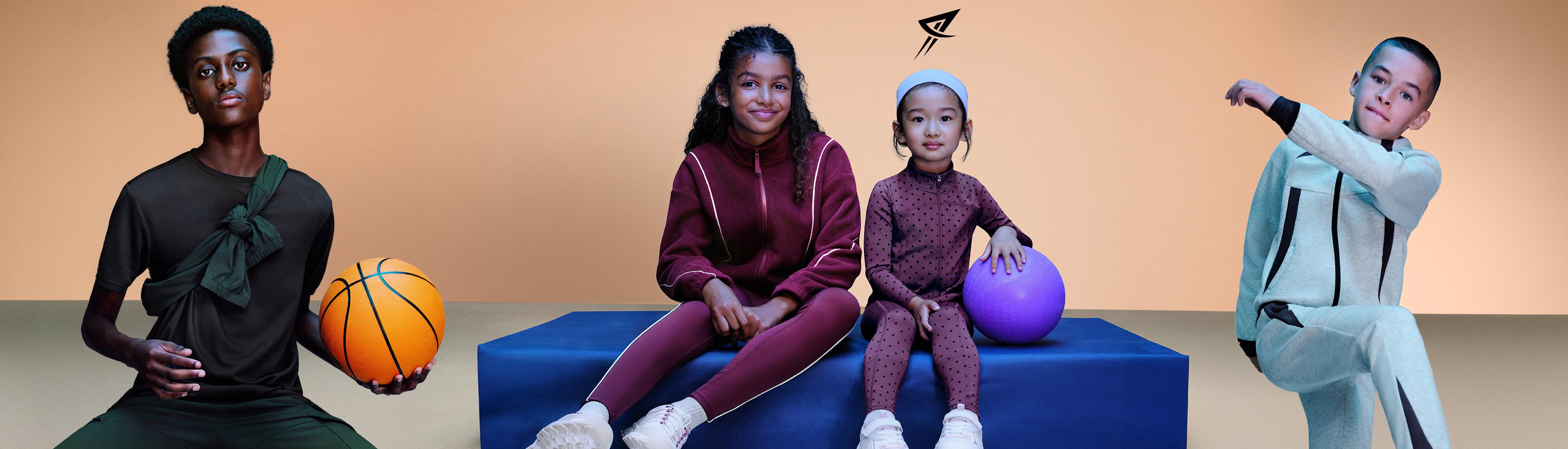Four young people wearing coordinating sportswear in various colours, posing with basketballs.