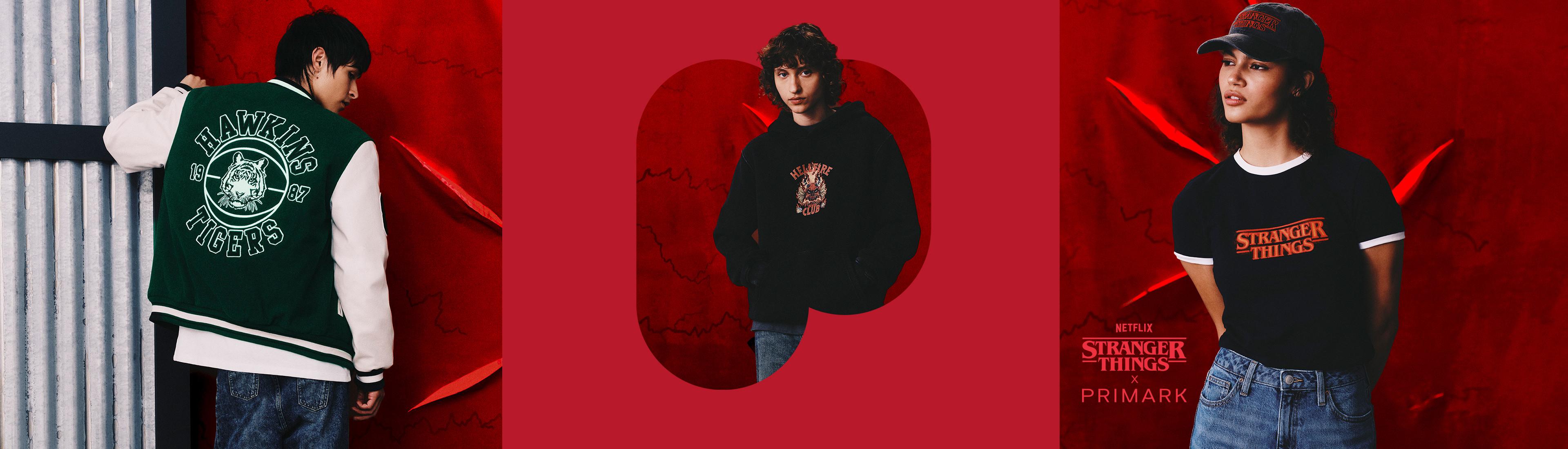 Stranger Things-Bekleidungskollektion mit College-Jacke, Hoodie und T-Shirt vor rotem Hintergrund.