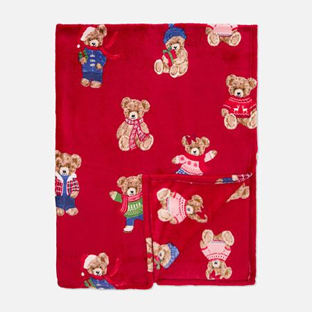 Red blanket with pattern of teddy bears wearing various colourful outfits and accessories.