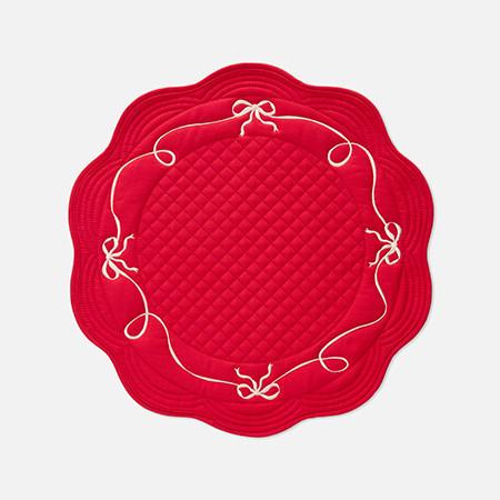 Bright red quilted placemat with scalloped edges and decorative cream bow embroidery around the border.