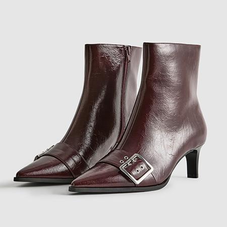 Burgundy leather ankle boots with pointed toes, slim heels and decorative buckle detail across the front.