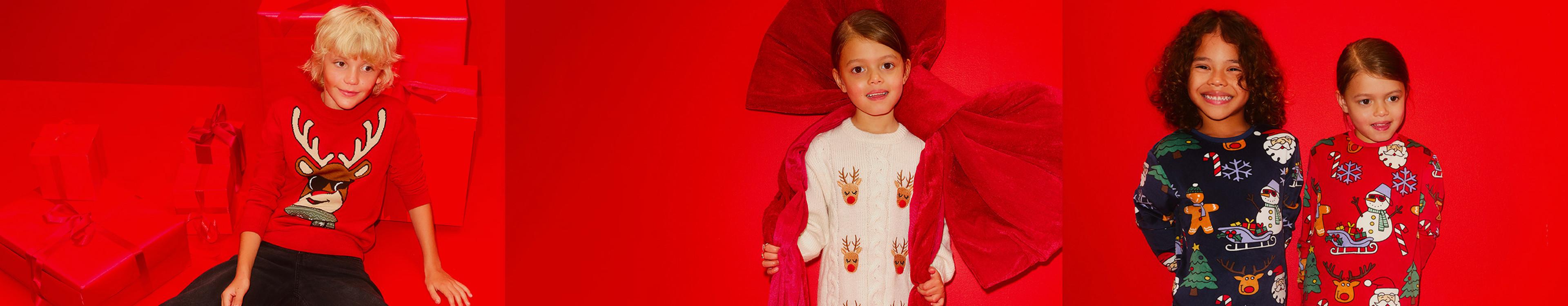 Children wearing festive Christmas jumpers featuring reindeer, snowmen and holiday designs against a red background.