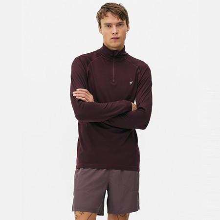 Burgundy half-zip athletic top with shorts, model standing with arms crossed.