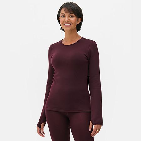 Woman wearing burgundy long sleeve athletic top with matching leggings, smiling at camera.