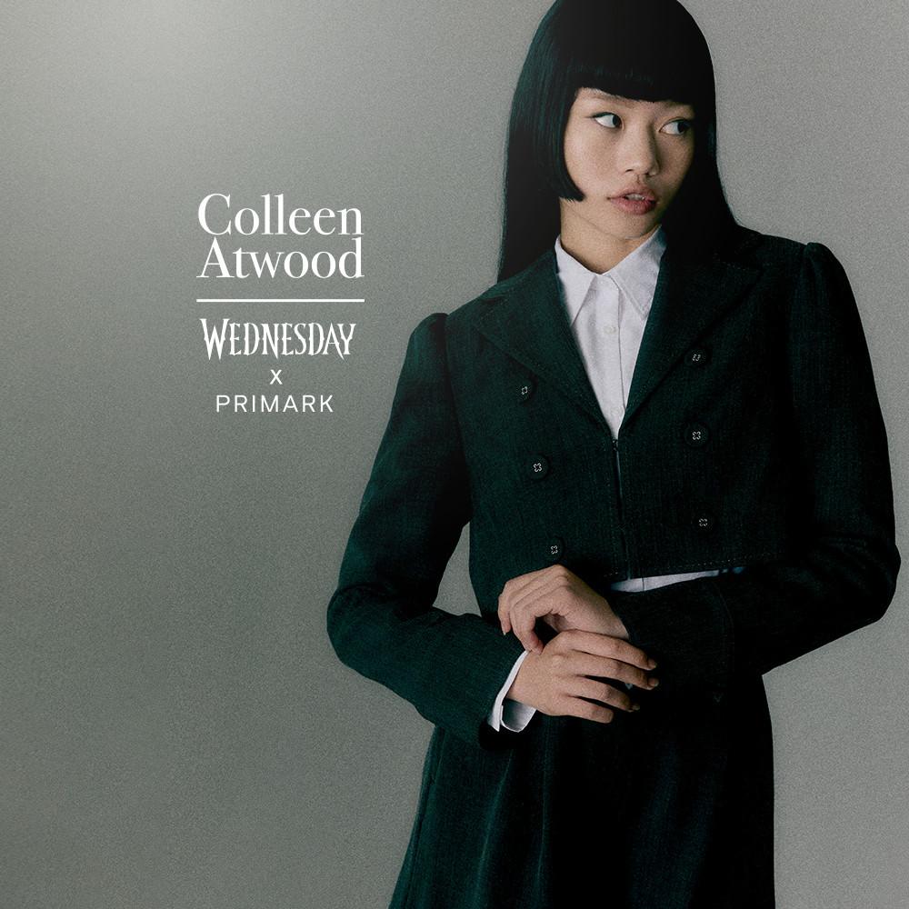 Model wearing a dark green coat with white shirt from Wednesday x Primark collection.