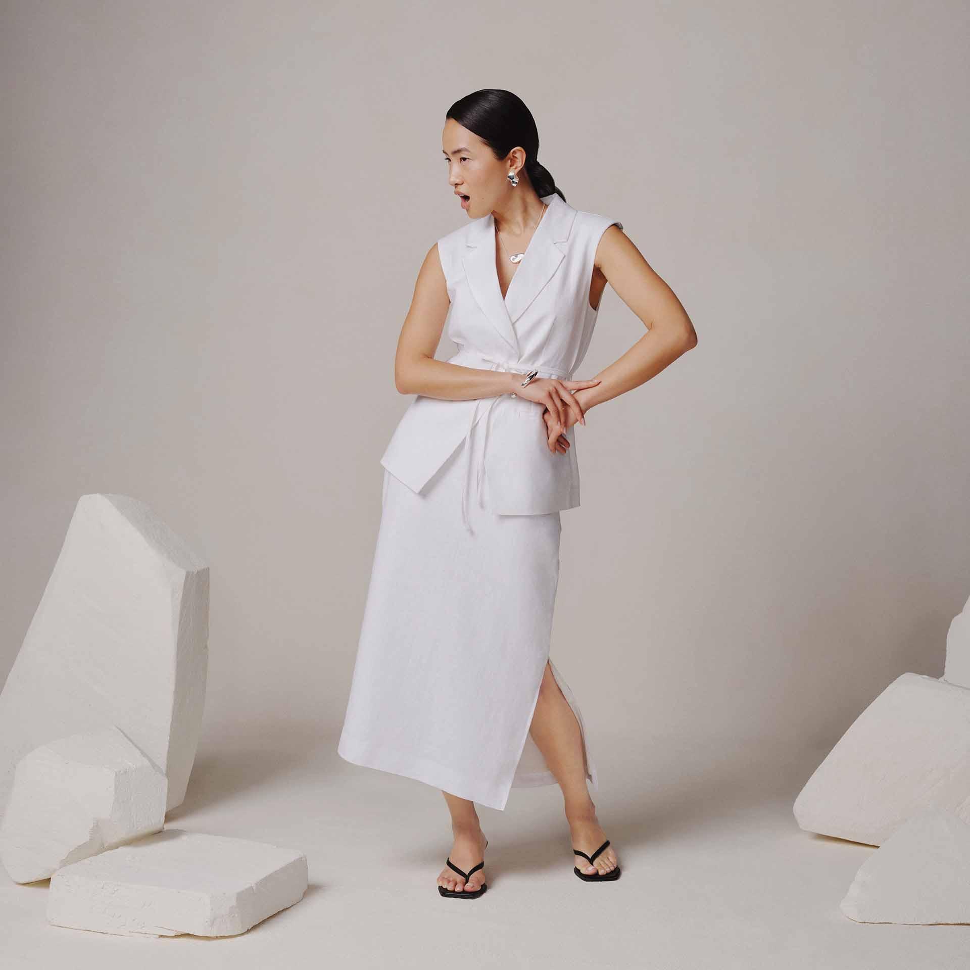 Women wearing a white linen co-ord with a surprised expression, on a neutral background.