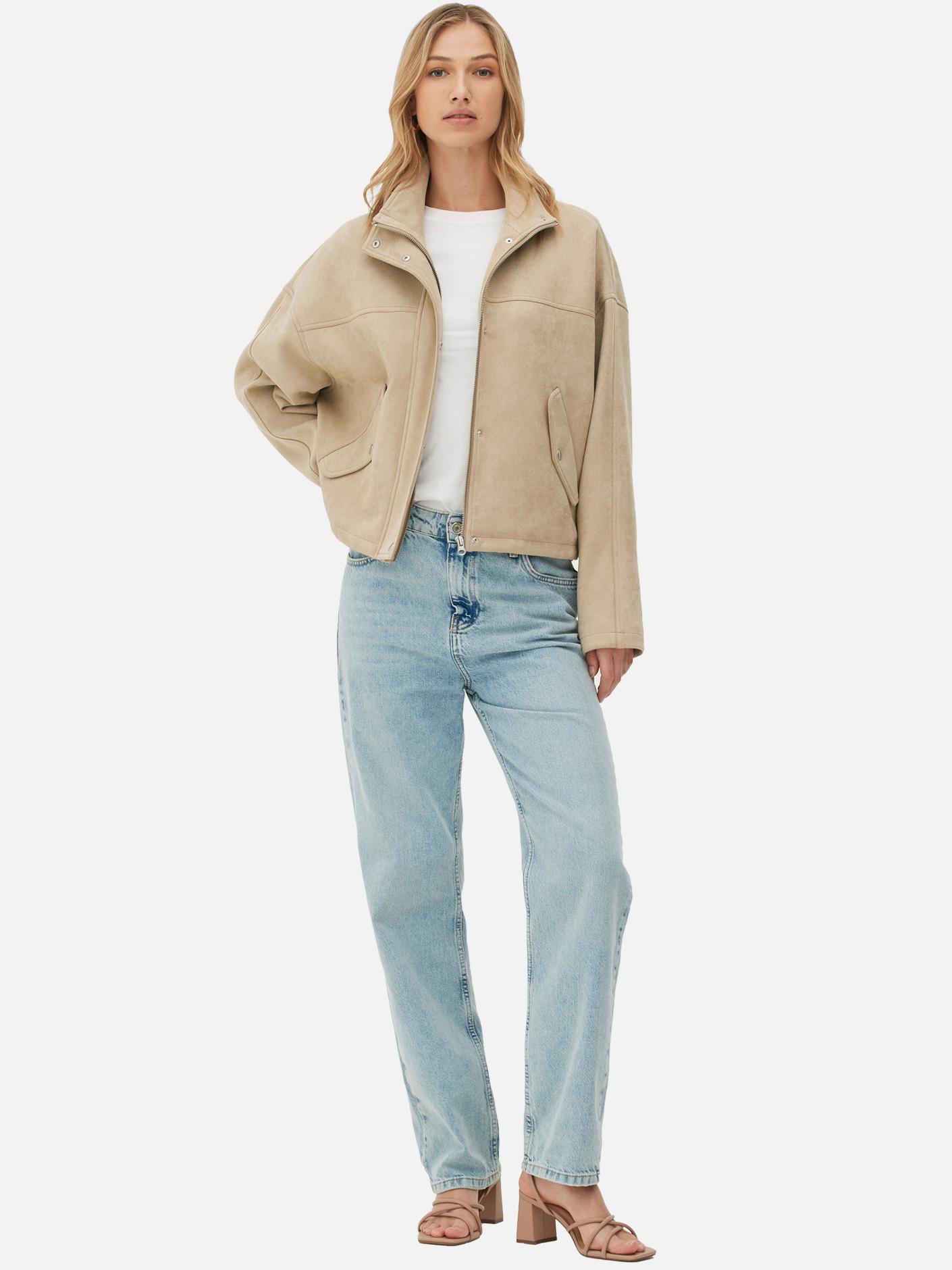 Model wears beige zip jacket, blue jeans and white tee