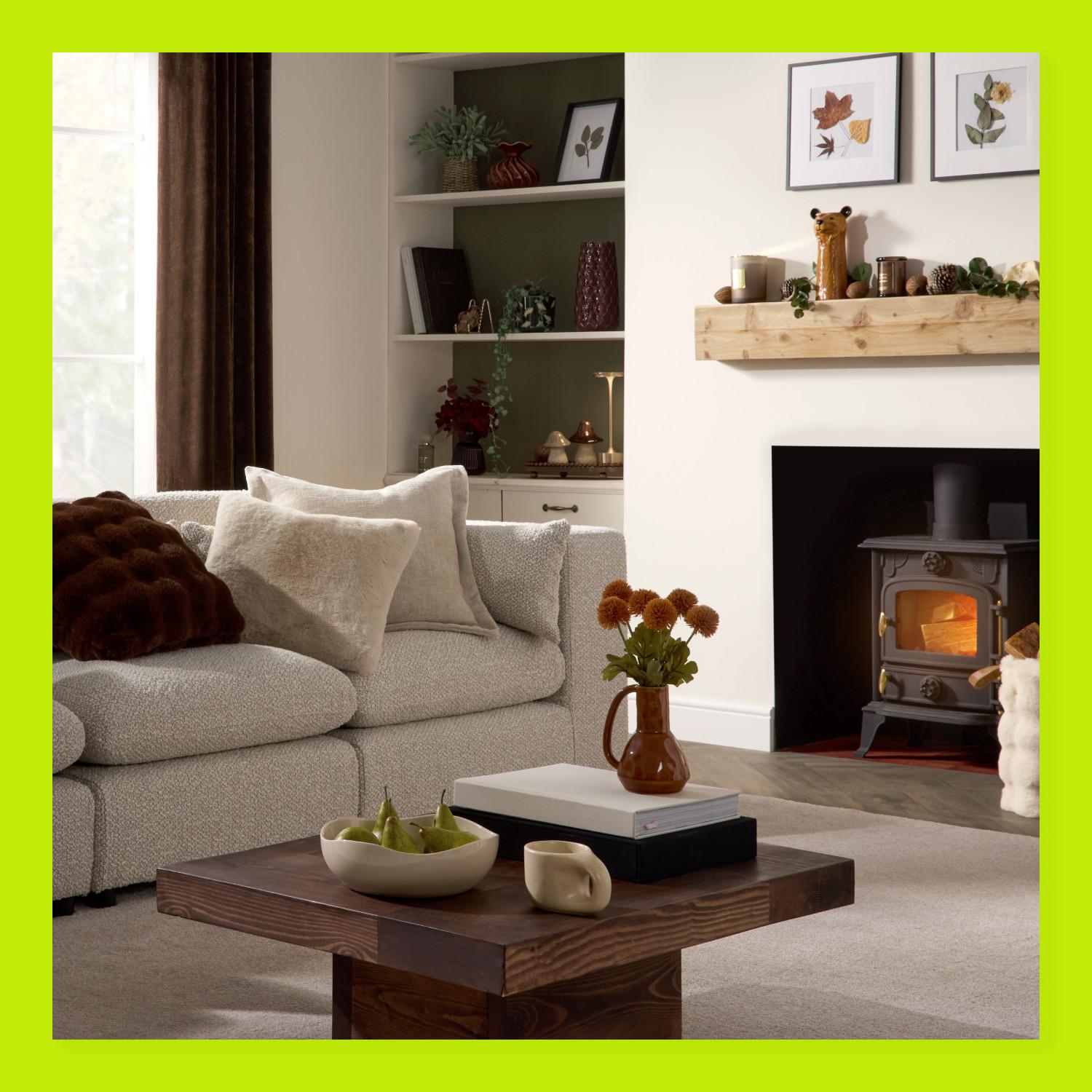 Cosy living room with grey sofa, wooden coffee table, wood-burning stove and rustic wooden mantelpiece.
