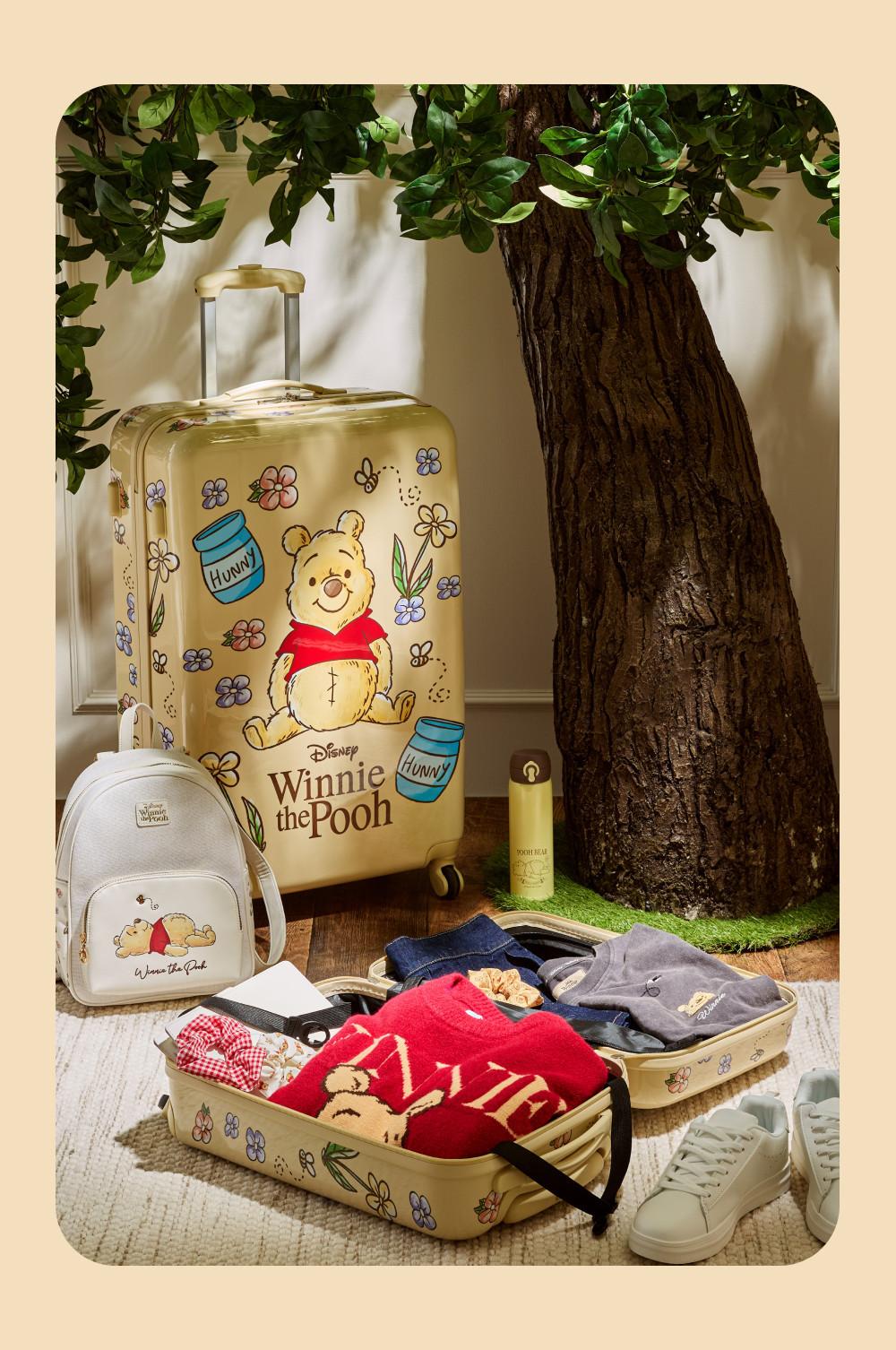 Disney Winnie the Pooh luggage set featuring suitcase, backpack and open case with folded clothing next to white trainers.