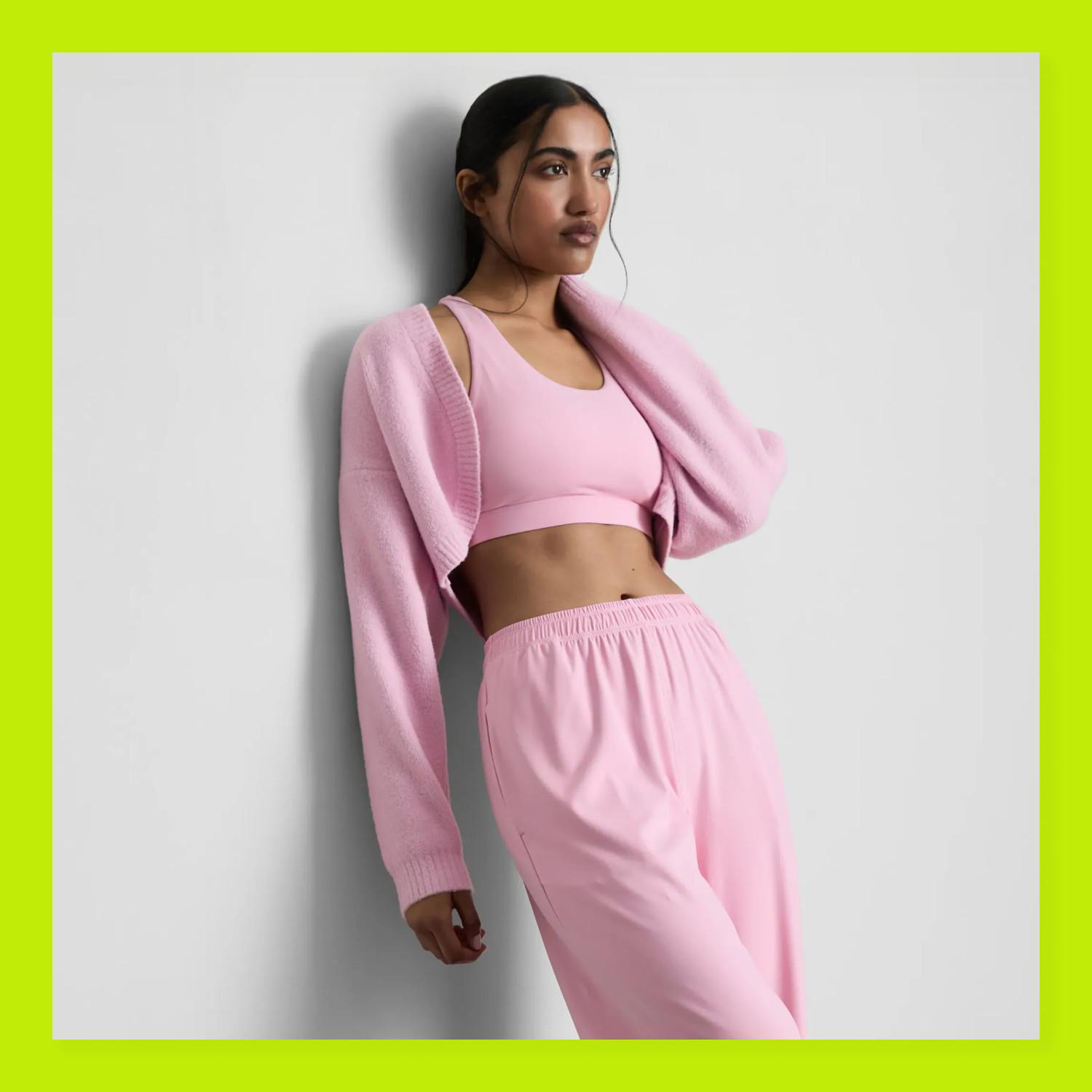 Pink athleisure set featuring crop top, loose joggers and matching cardigan against white background.