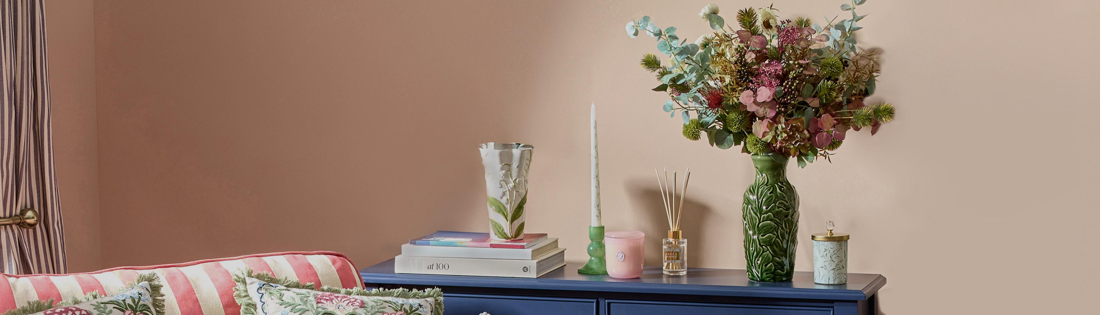 Blue chest of drawers with books, two vases, candlestick, candles and a diffuser