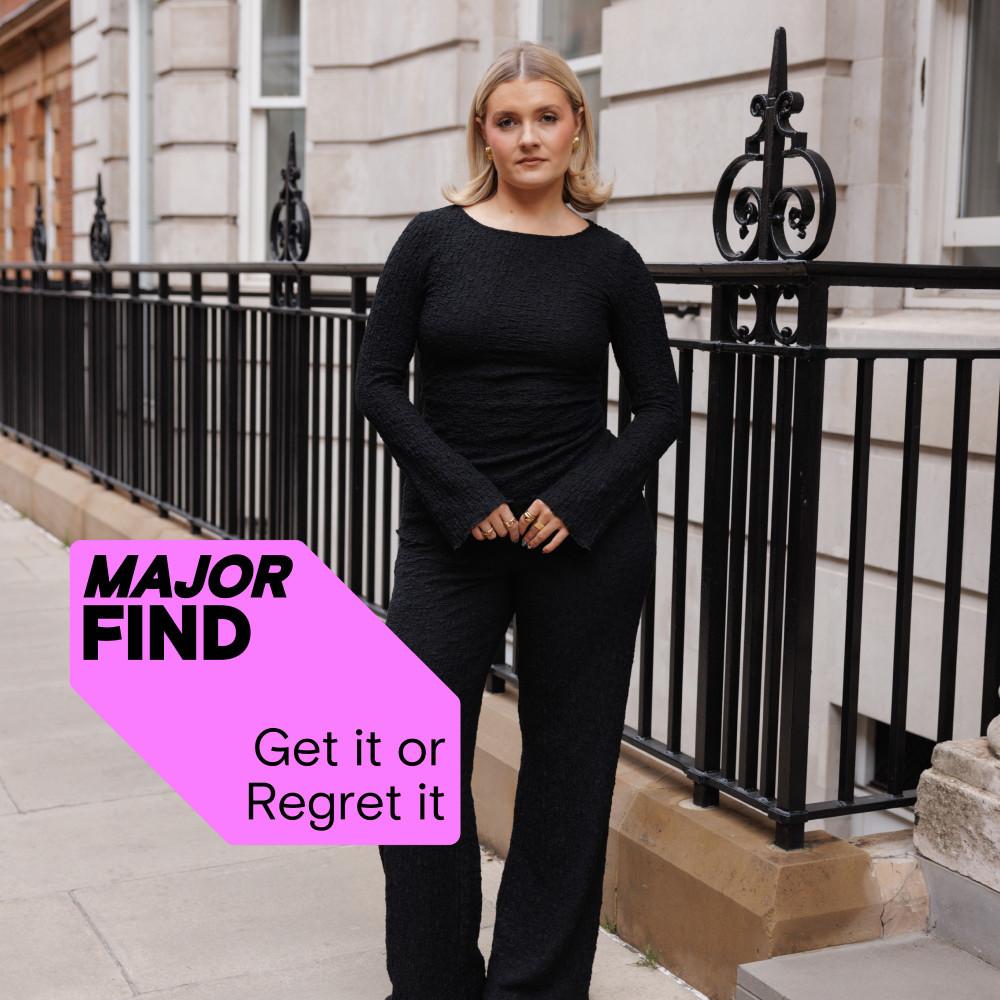 Elegant black textured jumpsuit with long sleeves against ornate railings. Pink label reads "MAJOR FIND Get it or Regret it".