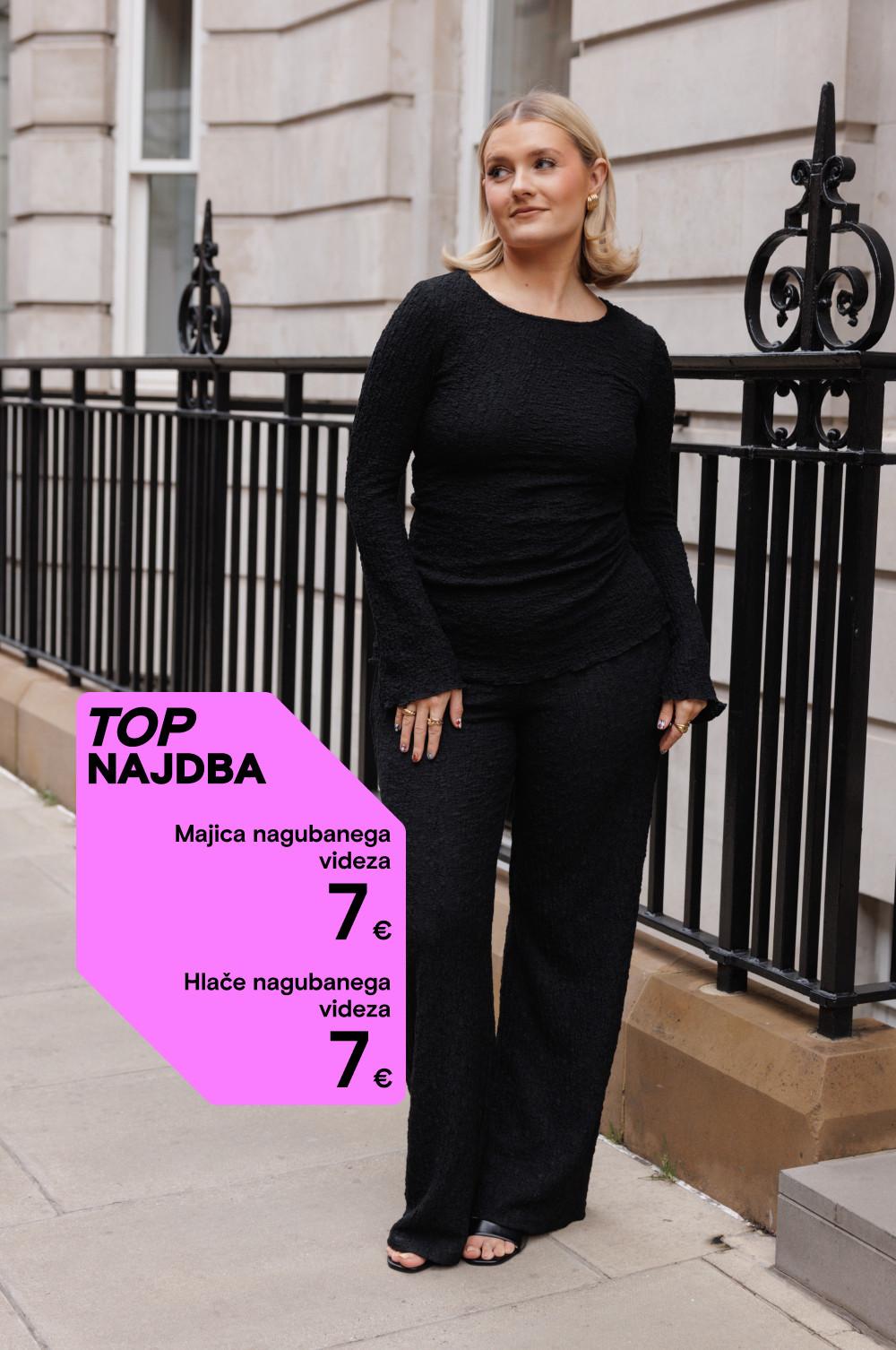 Oseba v črnem topu in hlačah zmečkanega videza stoji ob okrašeni ograji. Rožnata promocijska oznaka prikazuje 7 € za vsak kos.