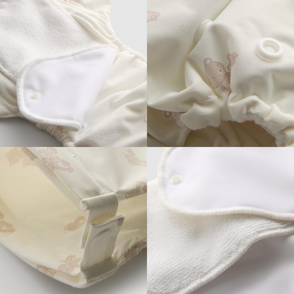 Primer plano de una prenda de bebé que muestra un tejido suave, cierre de botones y un sutil estampado de ositos.