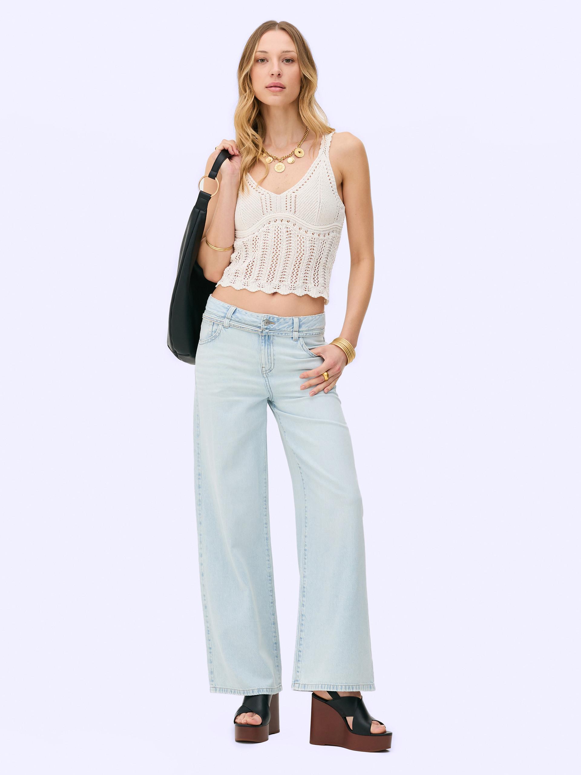 Model wearing knitted bralette with light blue jeans