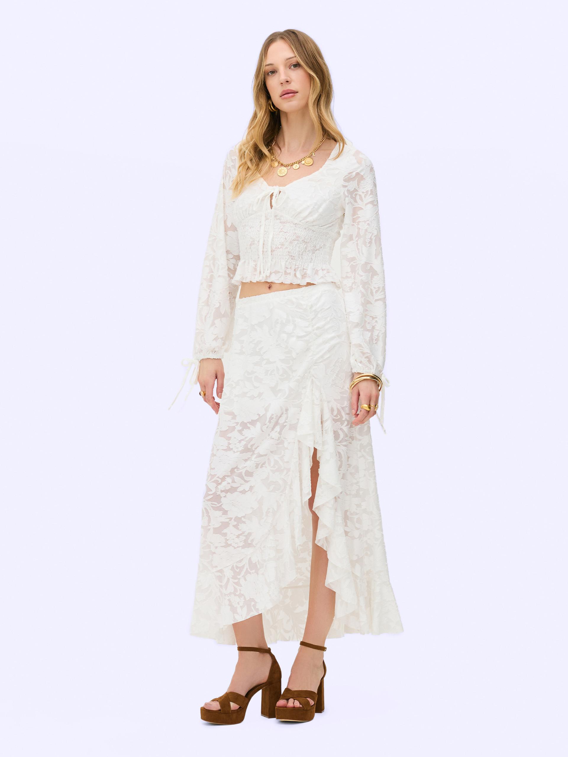 Model wears white lace top with matching midi skirt