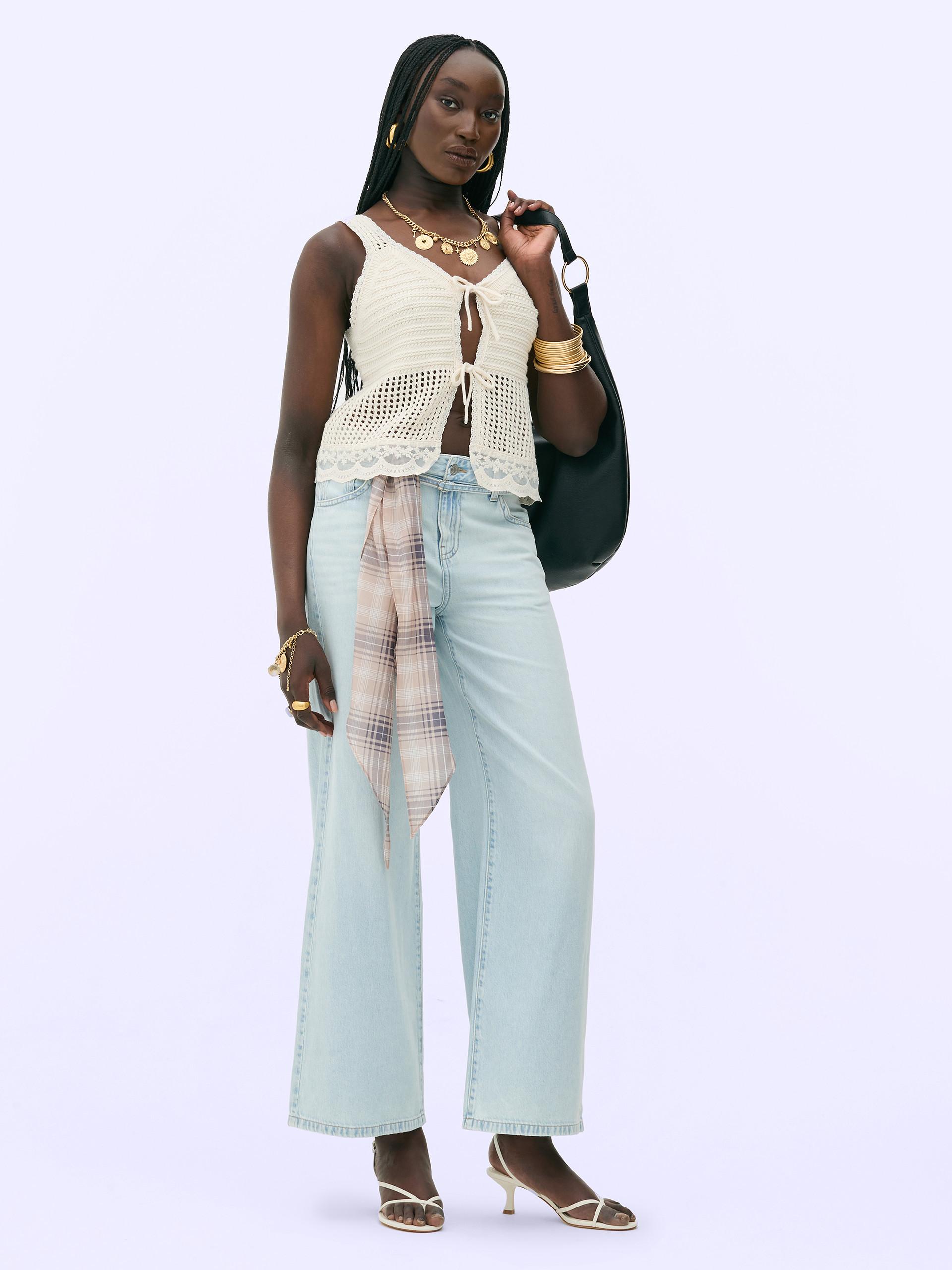 Model wears lace waistcoat with light blue jeans