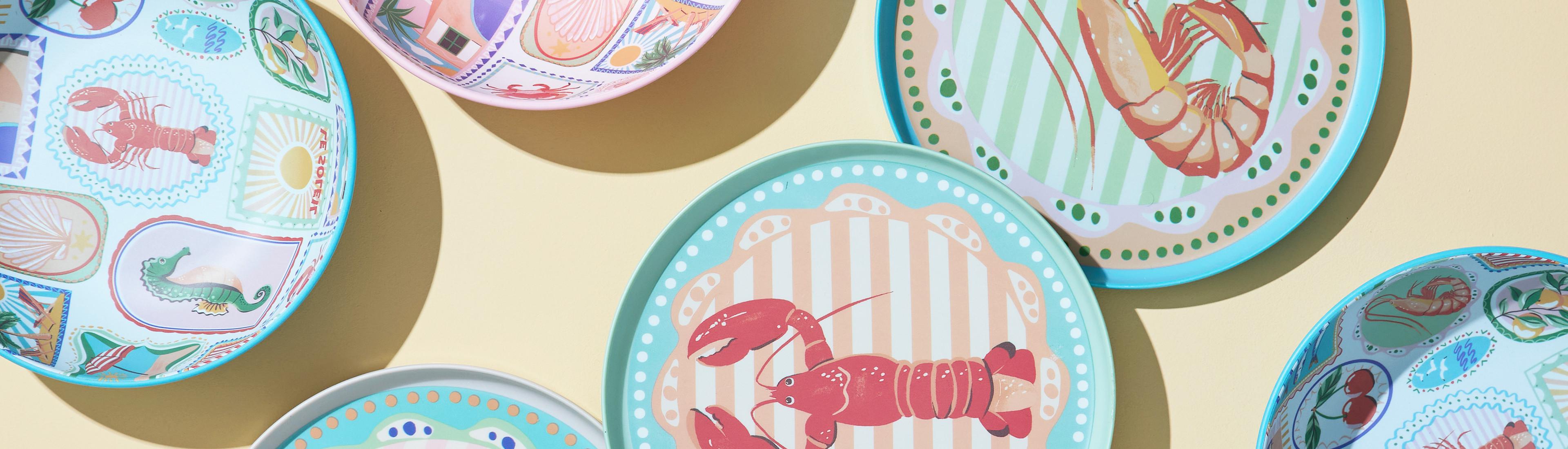 Decoratieve borden met een kustthema en afbeeldingen van zeedieren, waaronder een kreeft en garnaal, en ontwerpen met een zeethema plus pastelkleurige randen en patronen.