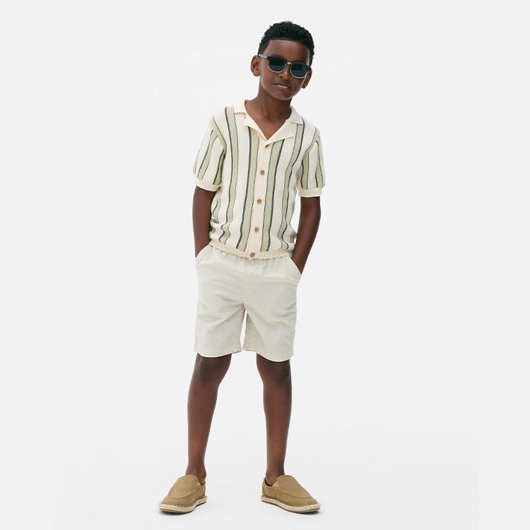 Kid wearing strippy short sleeved shirt and shorts