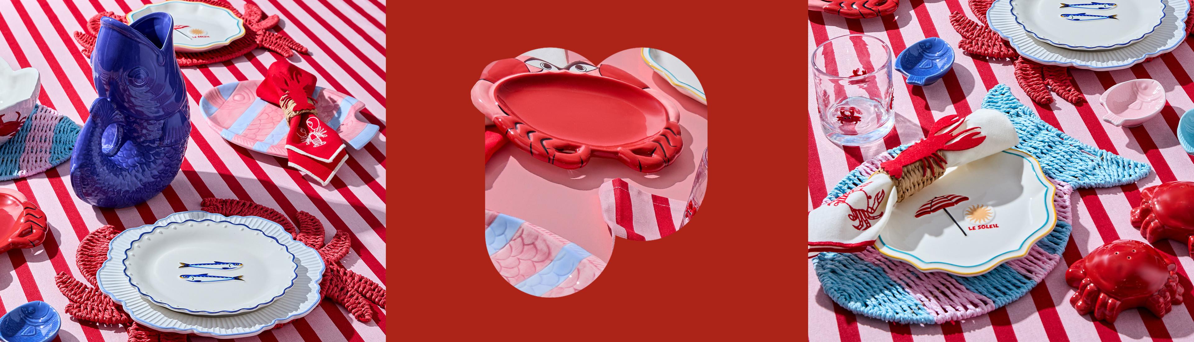 Mediterranean homeware set on a stippy red table including gulg jug, red crab theme plates and glassware.