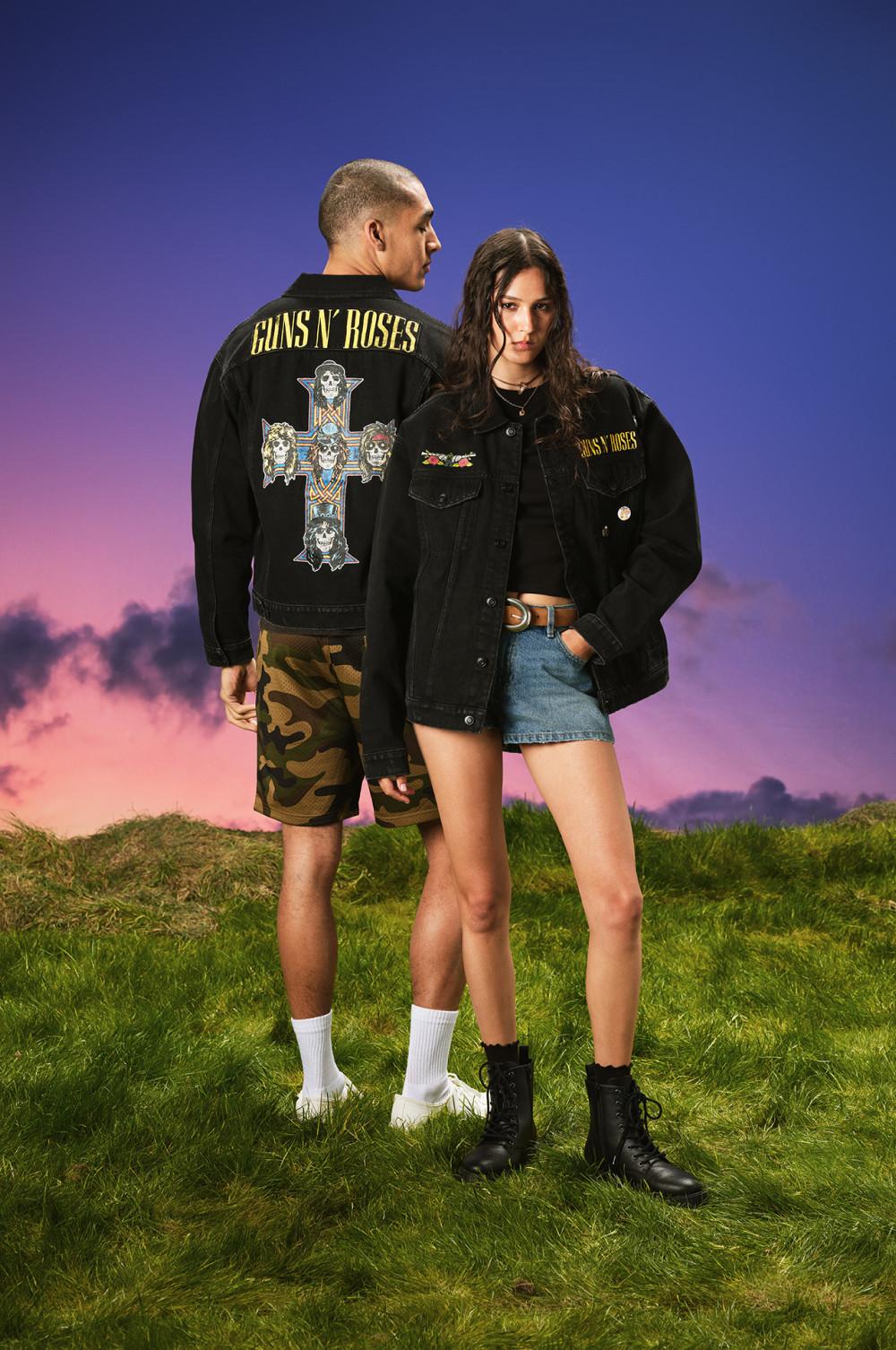 Two models wearing black Guns N' Roses denim jackets with graphic prints, paired with casual shorts.