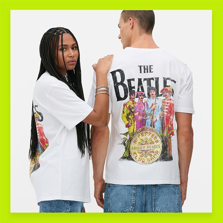 Two people wearing white The Beatles T-Shirts with blue denim bottoms.