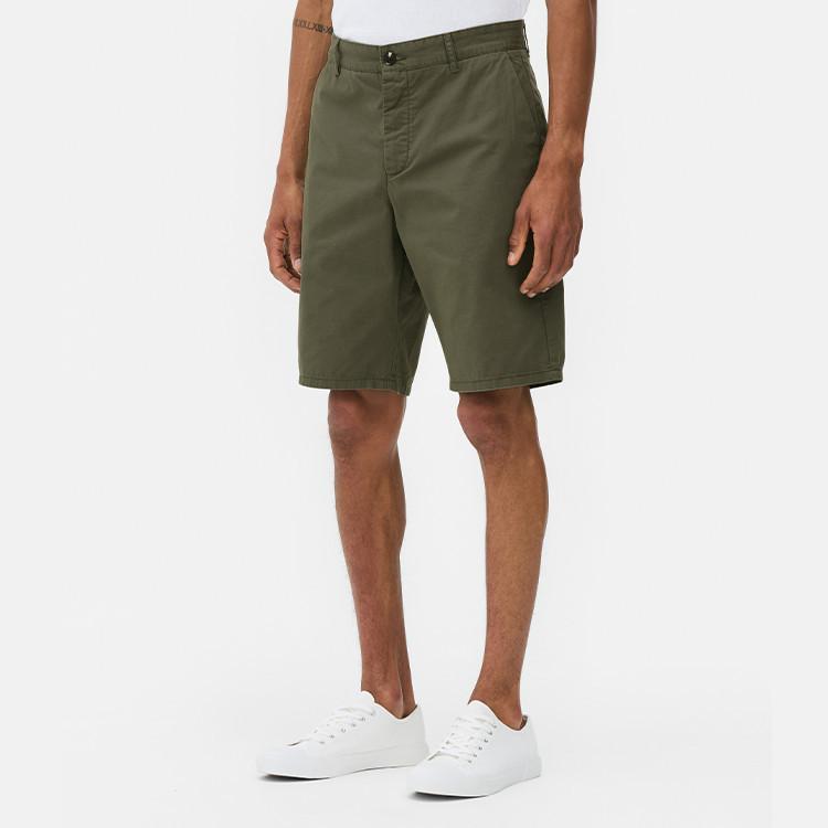 Person wearing olive green casual shorts with white trainers and partial view of white top.