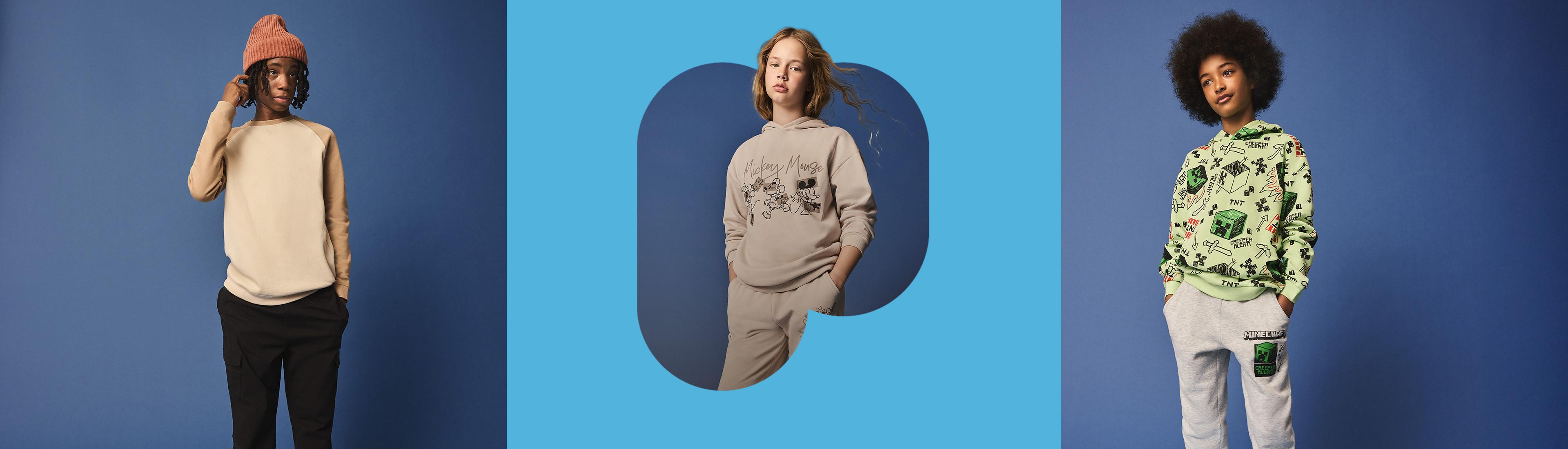 Trois enfants vêtus de vêtements décontractés, dont un pull gris, un sweat-shirt gris à motifs et un sweat à capuche à motifs gaming avec un bas assorti.