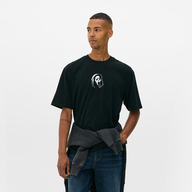 Person wearing black t-shirt with Ghostface logo, blue jeans and grey jacket tied around waist.